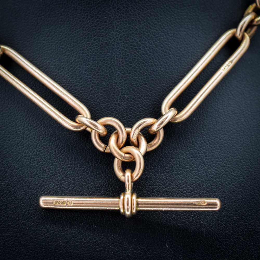 An Edwardian 9ct gold trombone link chain necklace with a central T-bar drop and dog clip clasp. View II