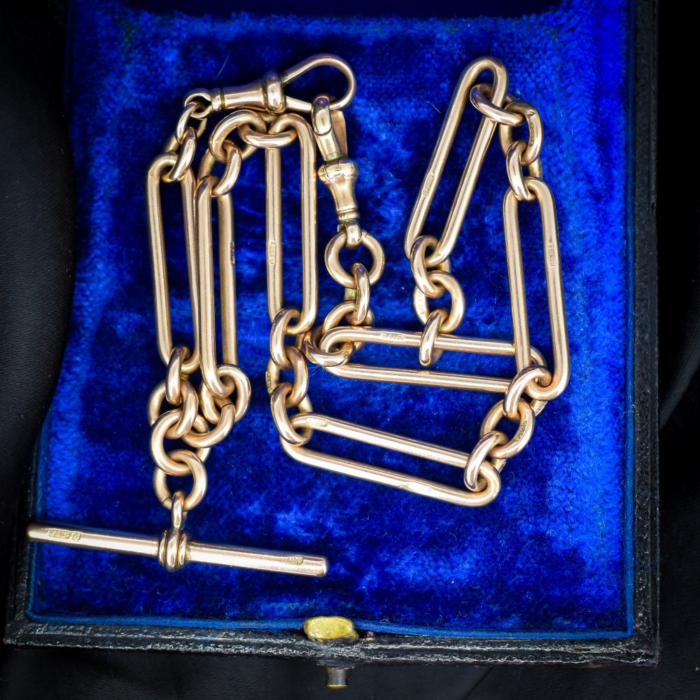 An Edwardian 9ct gold trombone link chain necklace with a central T-bar drop and dog clip clasp. View V
