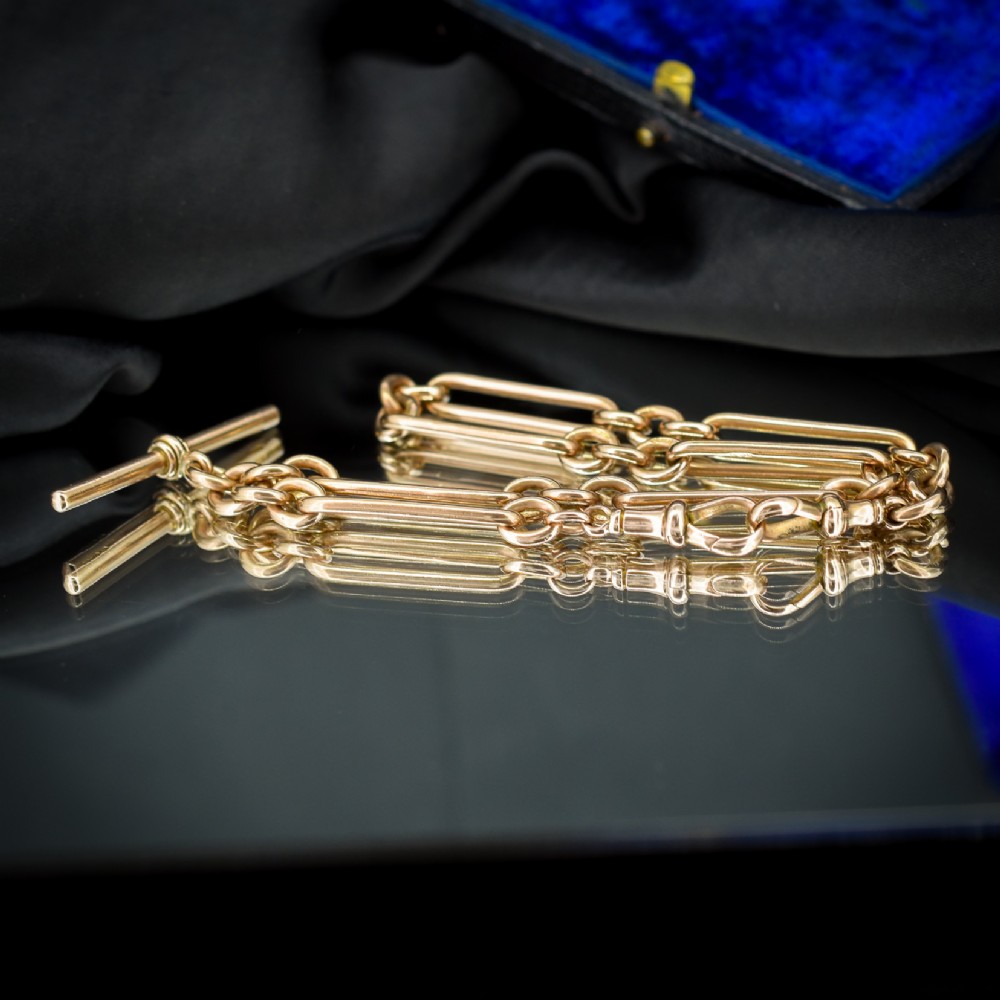 An Edwardian 9ct gold trombone link chain necklace with a central T-bar drop and dog clip clasp. View VI