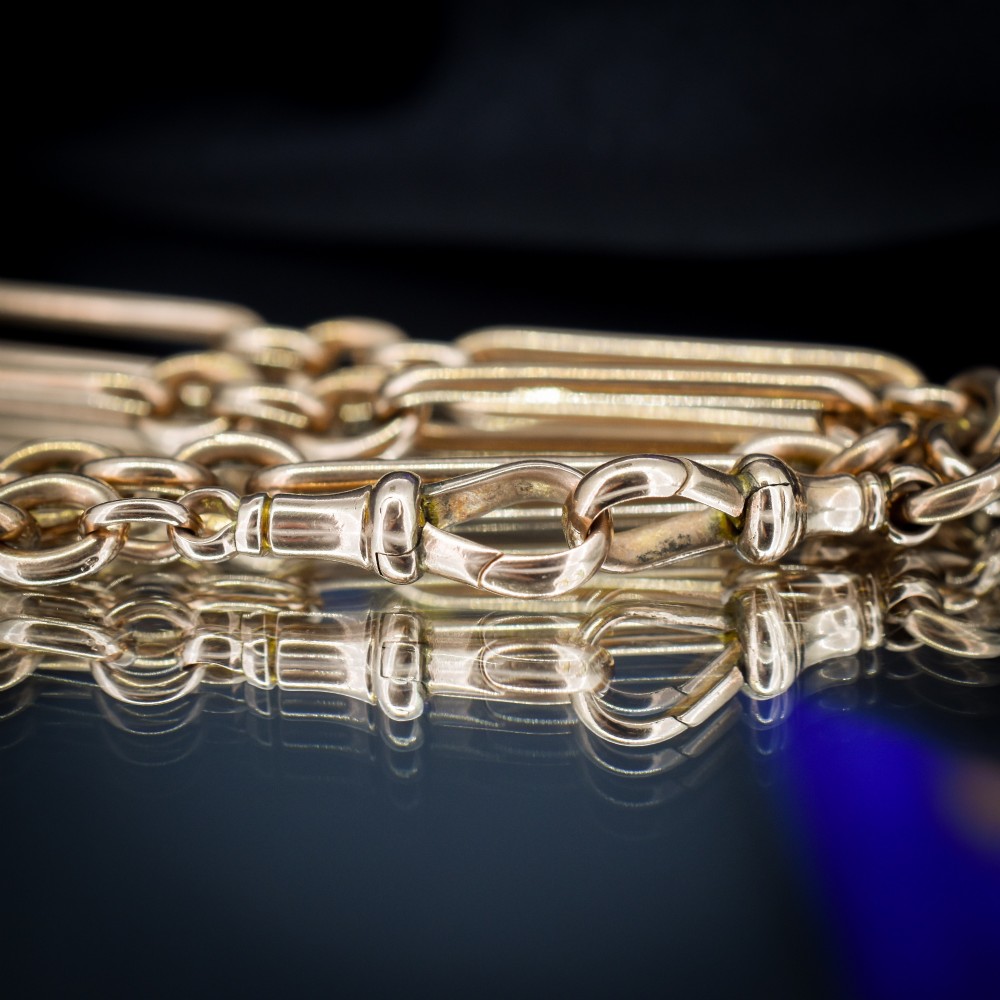 An Edwardian 9ct gold trombone link chain necklace with a central T-bar drop and dog clip clasp. View VII