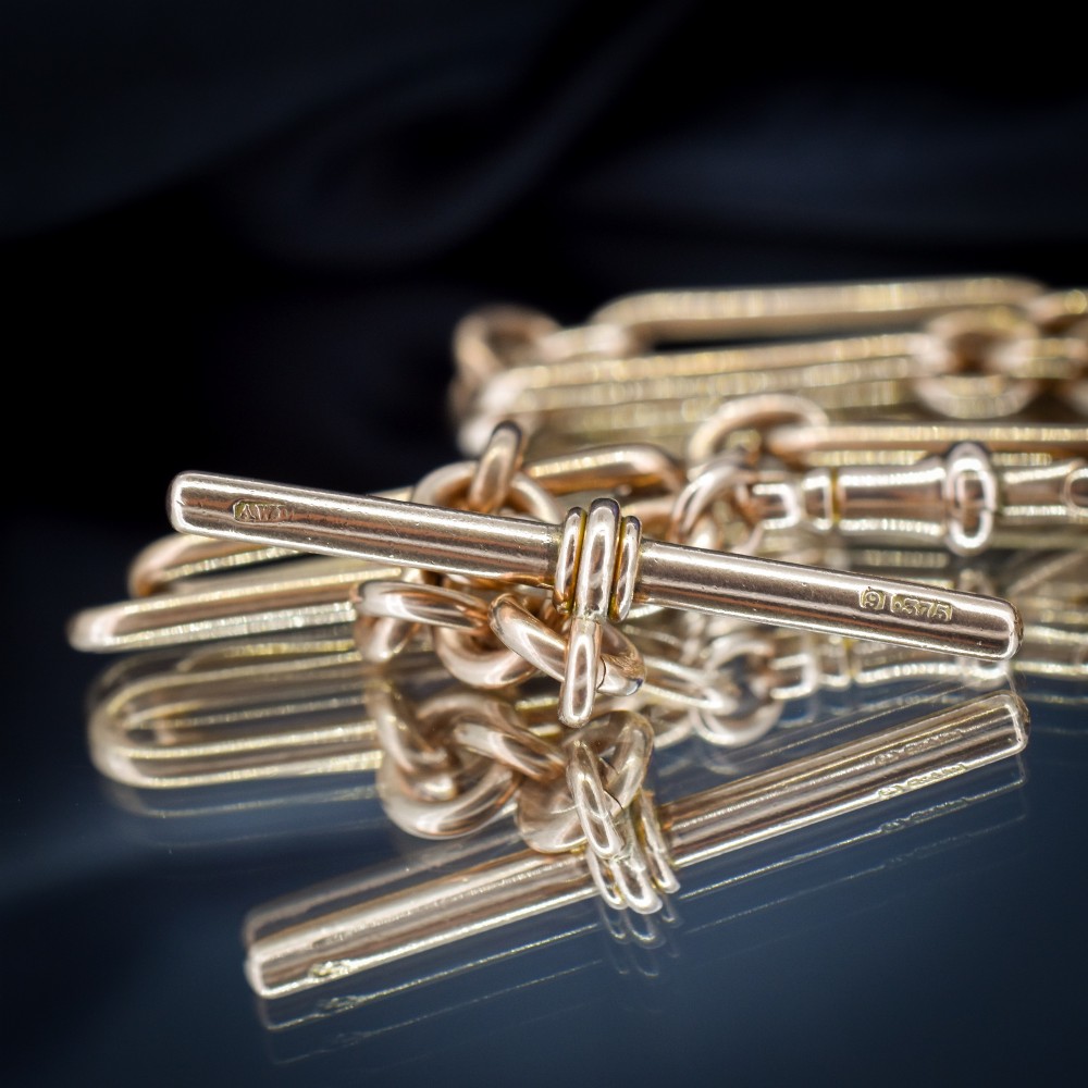 An Edwardian 9ct gold trombone link chain necklace with a central T-bar drop and dog clip clasp. View VIII