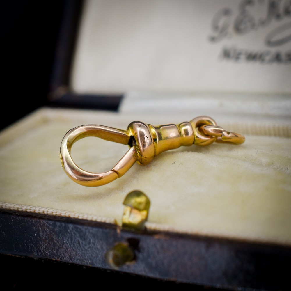 An antique 15ct yellow gold dog clip swivel clasp resting inside a silk-lined presentation box. View IV