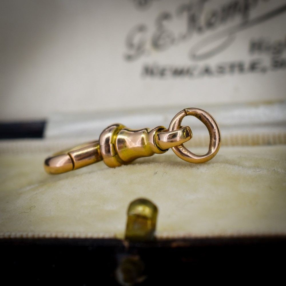 An antique 15ct yellow gold dog clip swivel clasp resting inside a silk-lined presentation box. View V