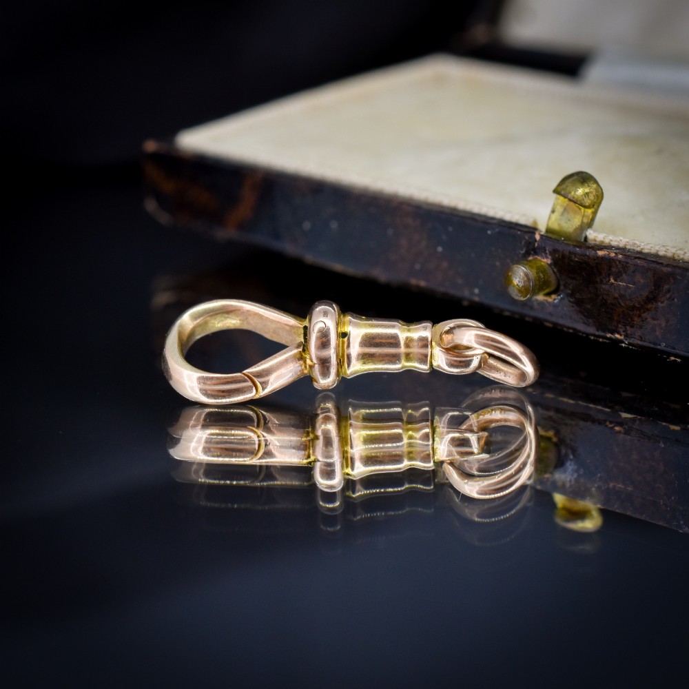 An antique 15ct yellow gold dog clip swivel clasp resting inside a silk-lined presentation box. View VI