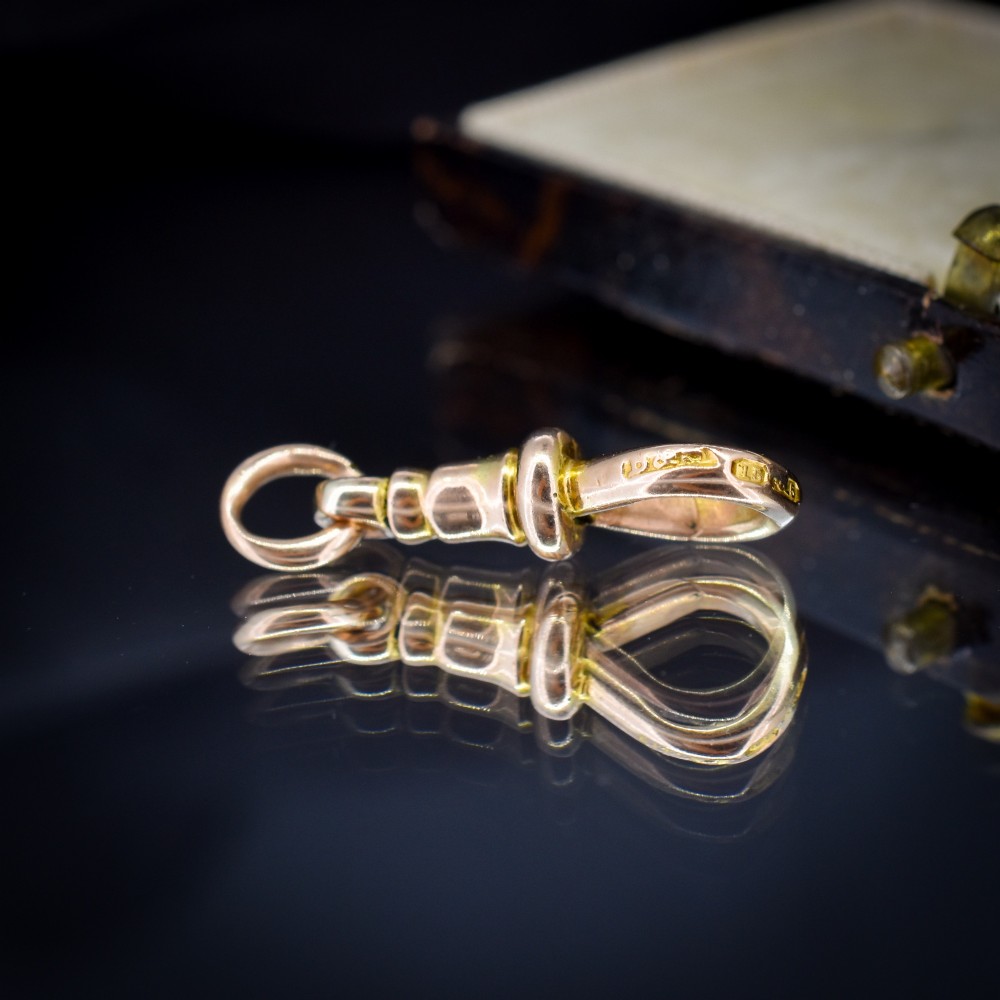 An antique 15ct yellow gold dog clip swivel clasp resting inside a silk-lined presentation box. View VII