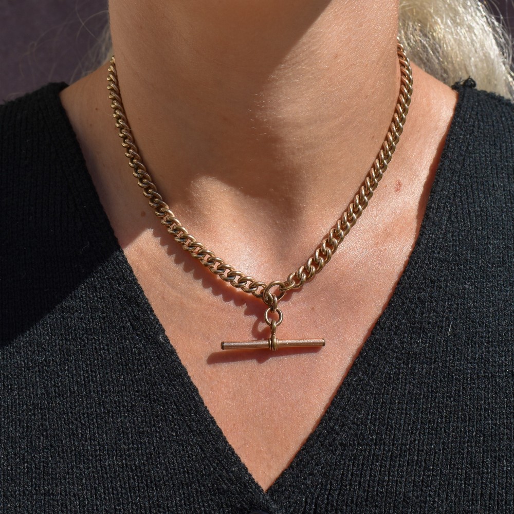 An antique rolled gold curb link watch chain featuring a central T-bar dropper and double dog clip fasteners. View X