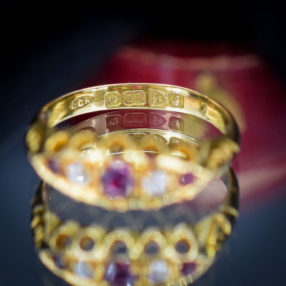 An antique 18ct yellow gold boat ring set with three round rubies alternating with two diamonds across a carved gallery setting. View VI
