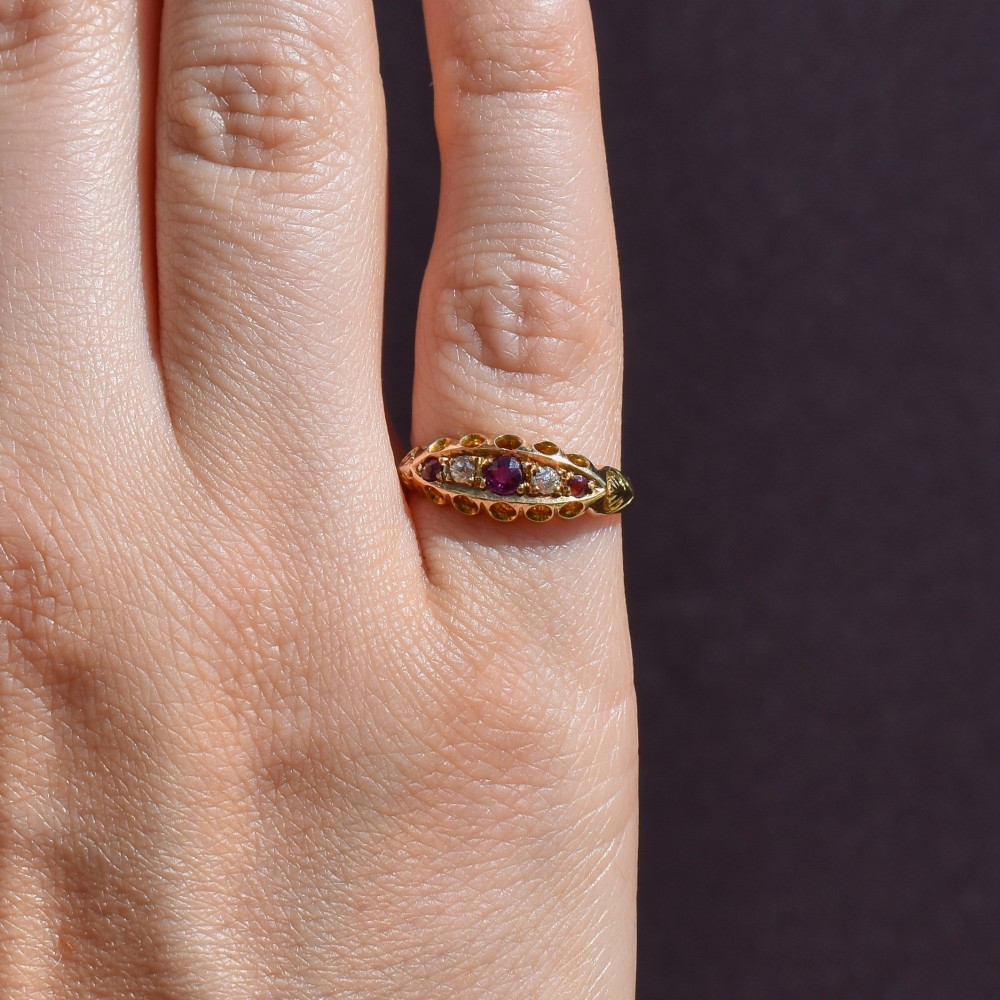 An antique 18ct yellow gold boat ring set with three round rubies alternating with two diamonds across a carved gallery setting. View VIII