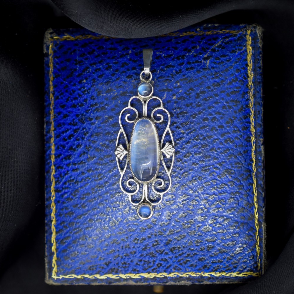 An antique sterling silver drop pendant featuring openwork scroll design set with an oval central moonstone cabochon and two smaller round moonstones. View II