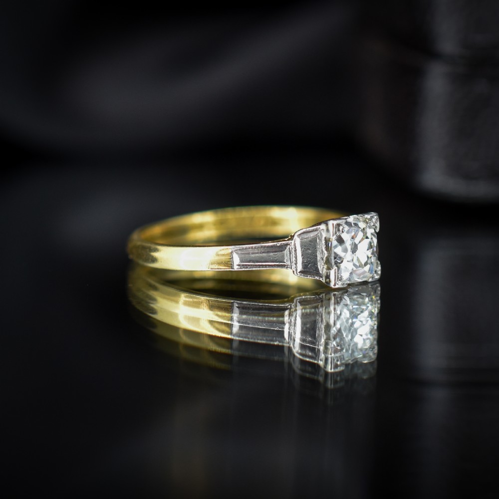 An Art Deco engagement ring featuring a square-set central old cut diamond on an 18ct yellow gold band with white metal stepped shoulders. View IV