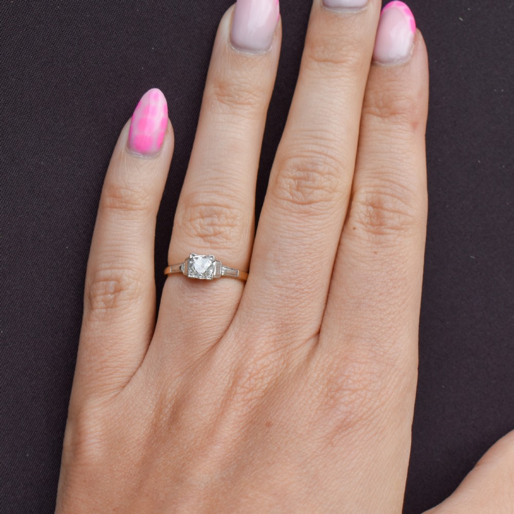 An Art Deco engagement ring featuring a square-set central old cut diamond on an 18ct yellow gold band with white metal stepped shoulders. View VII