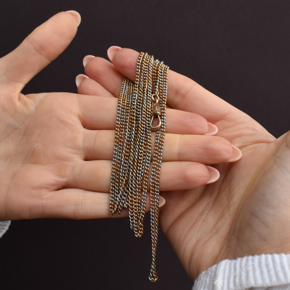 An antique multi-tone metal curb guard chain wrapped in multiple loops with an attached dog clip clasp. View VIII