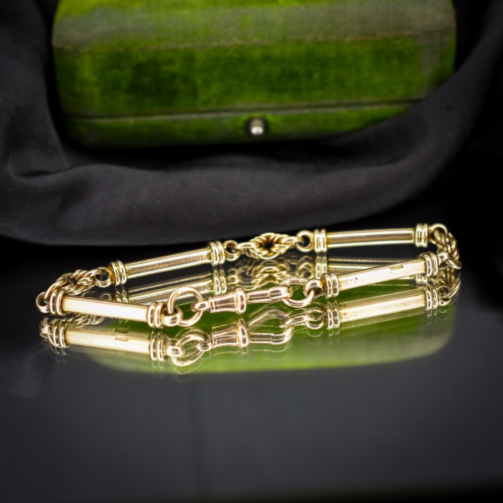 An antique 9ct yellow gold bracelet featuring elongated tubular bar links interspersed with love knot connections and a dog clip clasp. View II