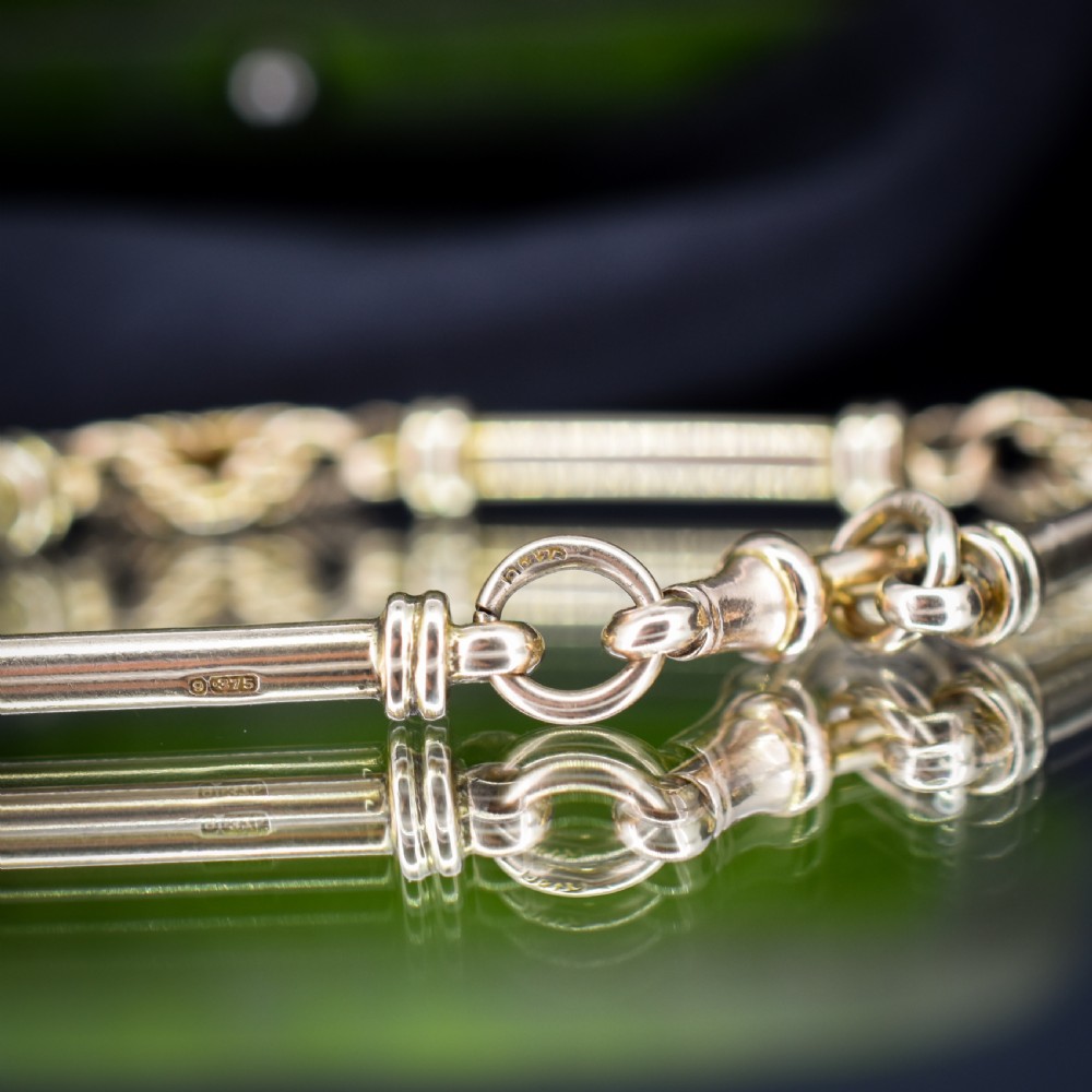 An antique 9ct yellow gold bracelet featuring elongated tubular bar links interspersed with love knot connections and a dog clip clasp. View V