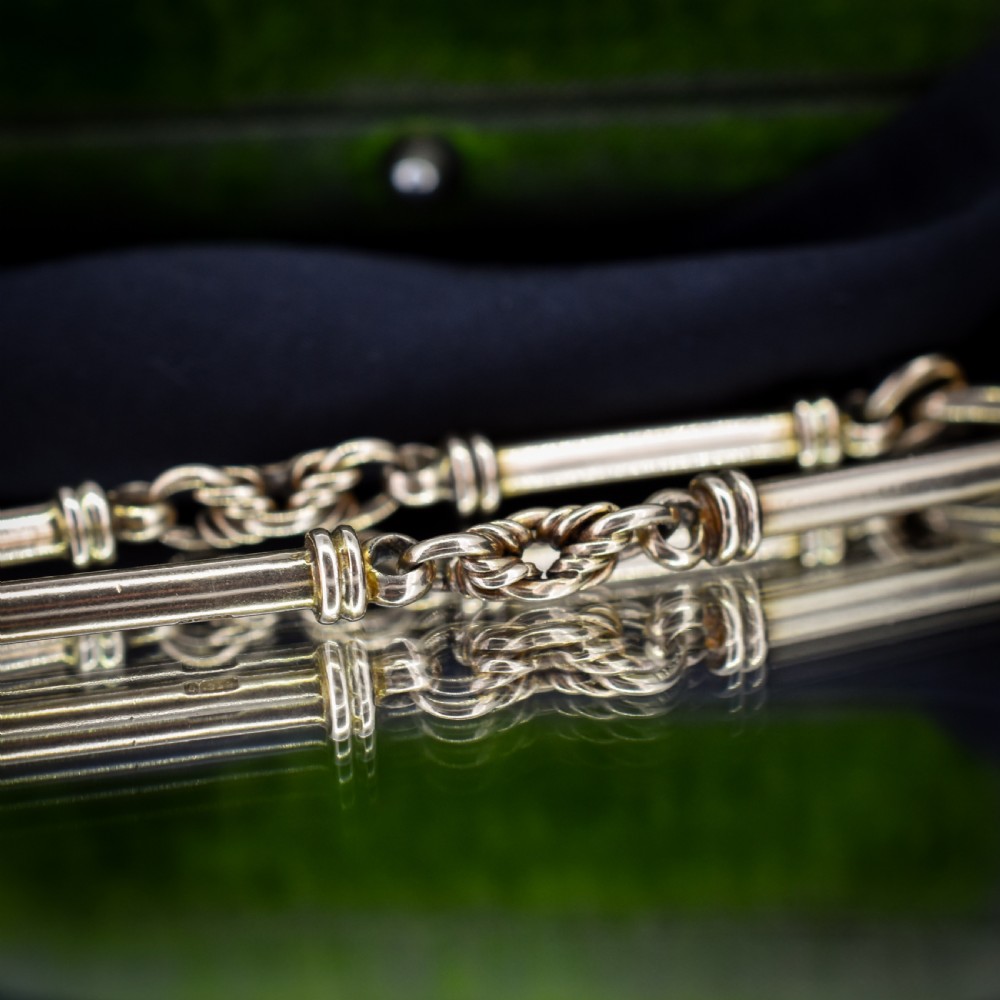 An antique 9ct yellow gold bracelet featuring elongated tubular bar links interspersed with love knot connections and a dog clip clasp. View VI