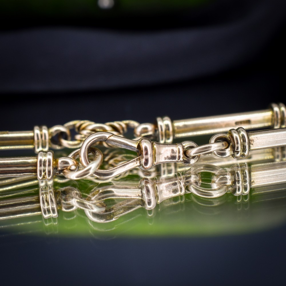 An antique 9ct yellow gold bracelet featuring elongated tubular bar links interspersed with love knot connections and a dog clip clasp. View VII