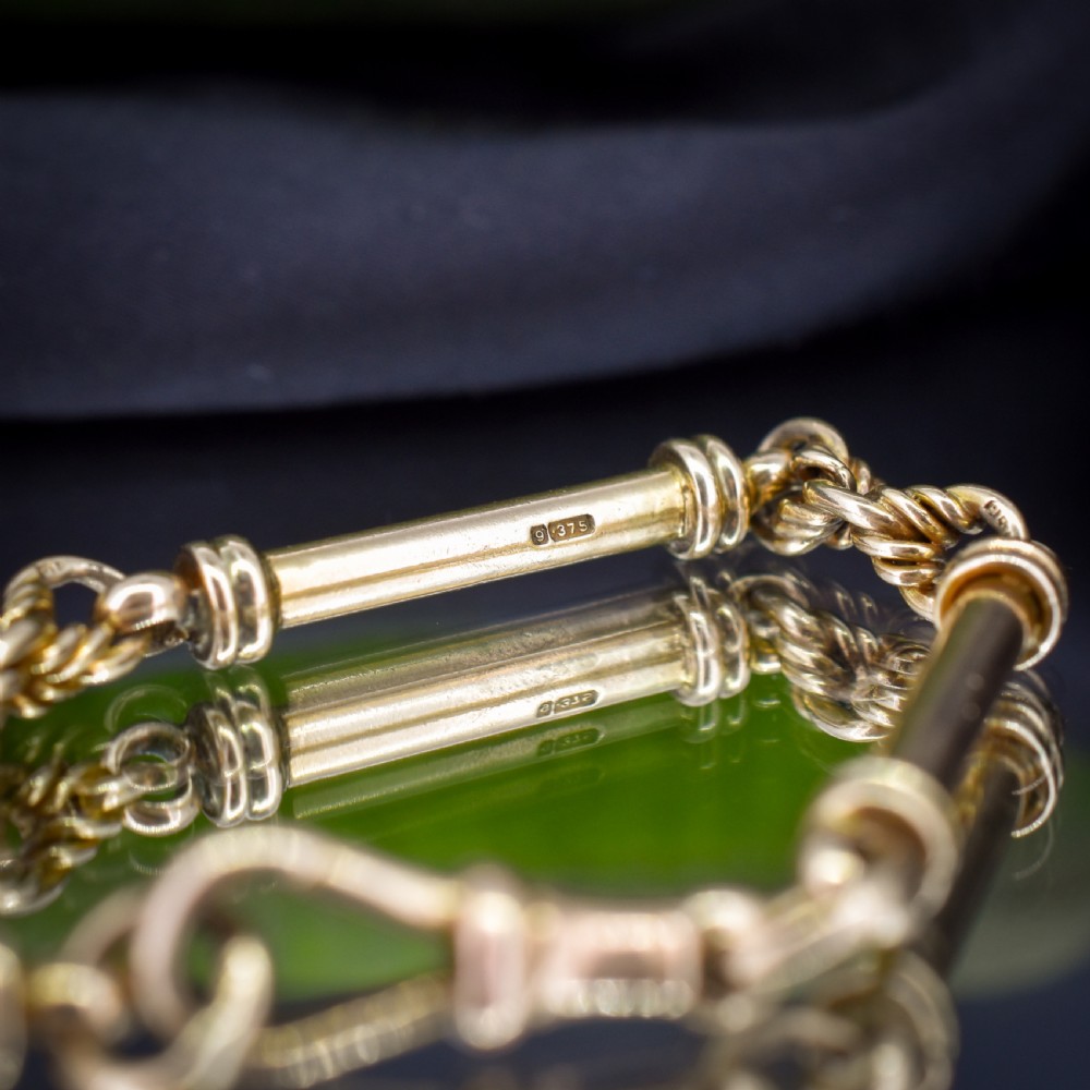 An antique 9ct yellow gold bracelet featuring elongated tubular bar links interspersed with love knot connections and a dog clip clasp. View VIII
