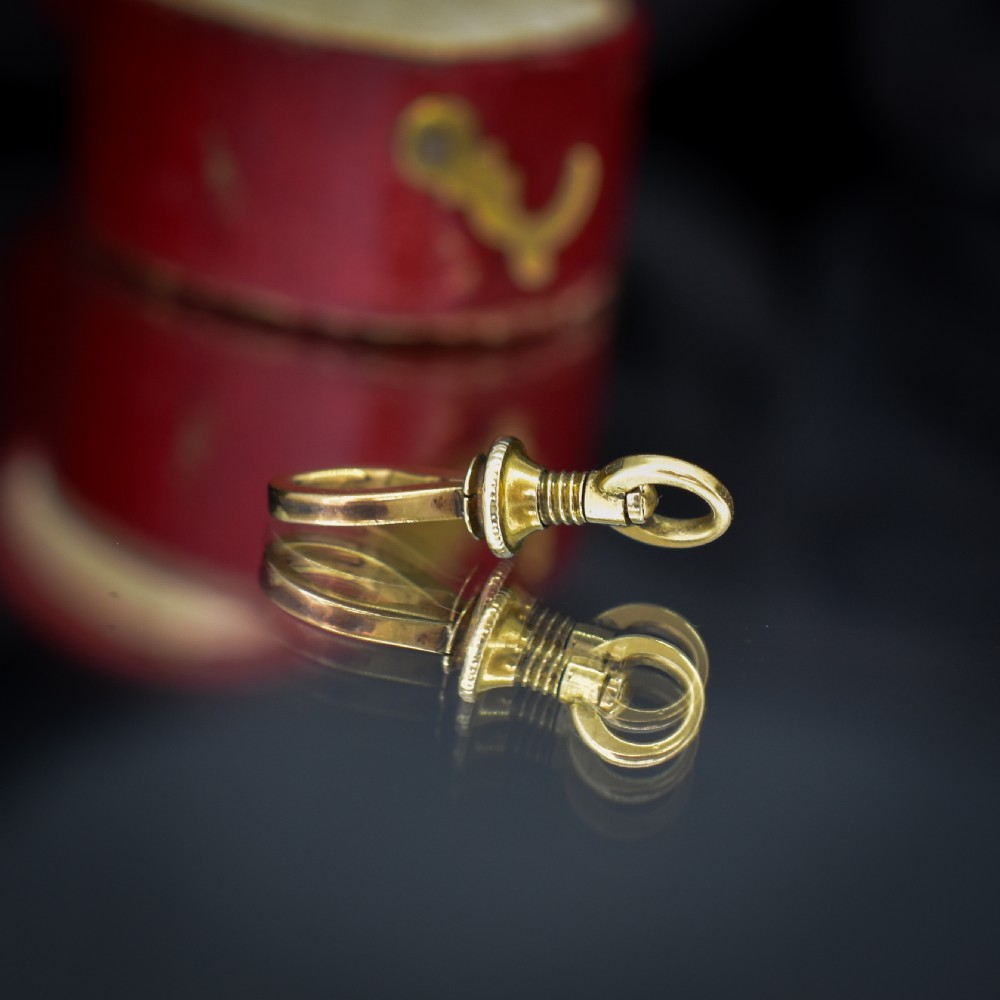 An antique 15ct yellow gold screw dog clip fastener resting on a red heart-shaped presentation box. View V