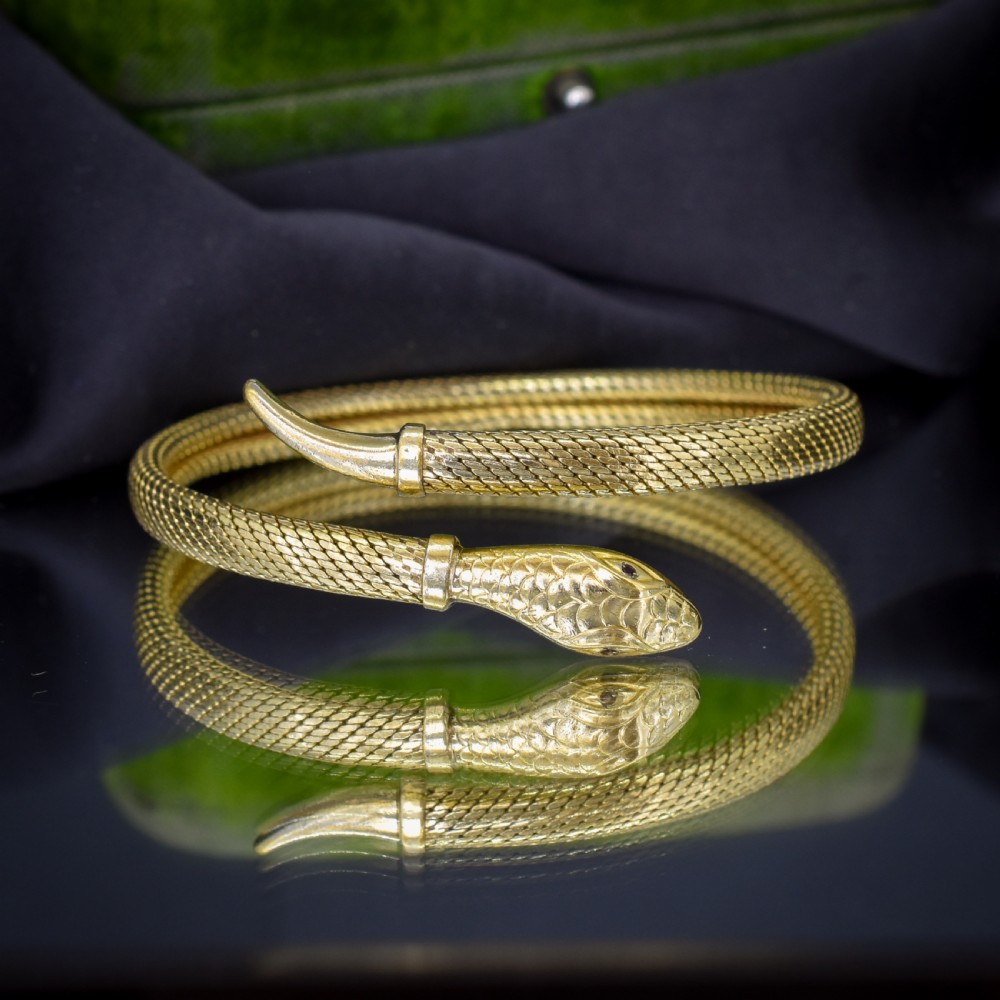 A rolled gold coiled snake bangle bracelet featuring detailed scale engraving, a sculpted head, and a tapered tail. View IV