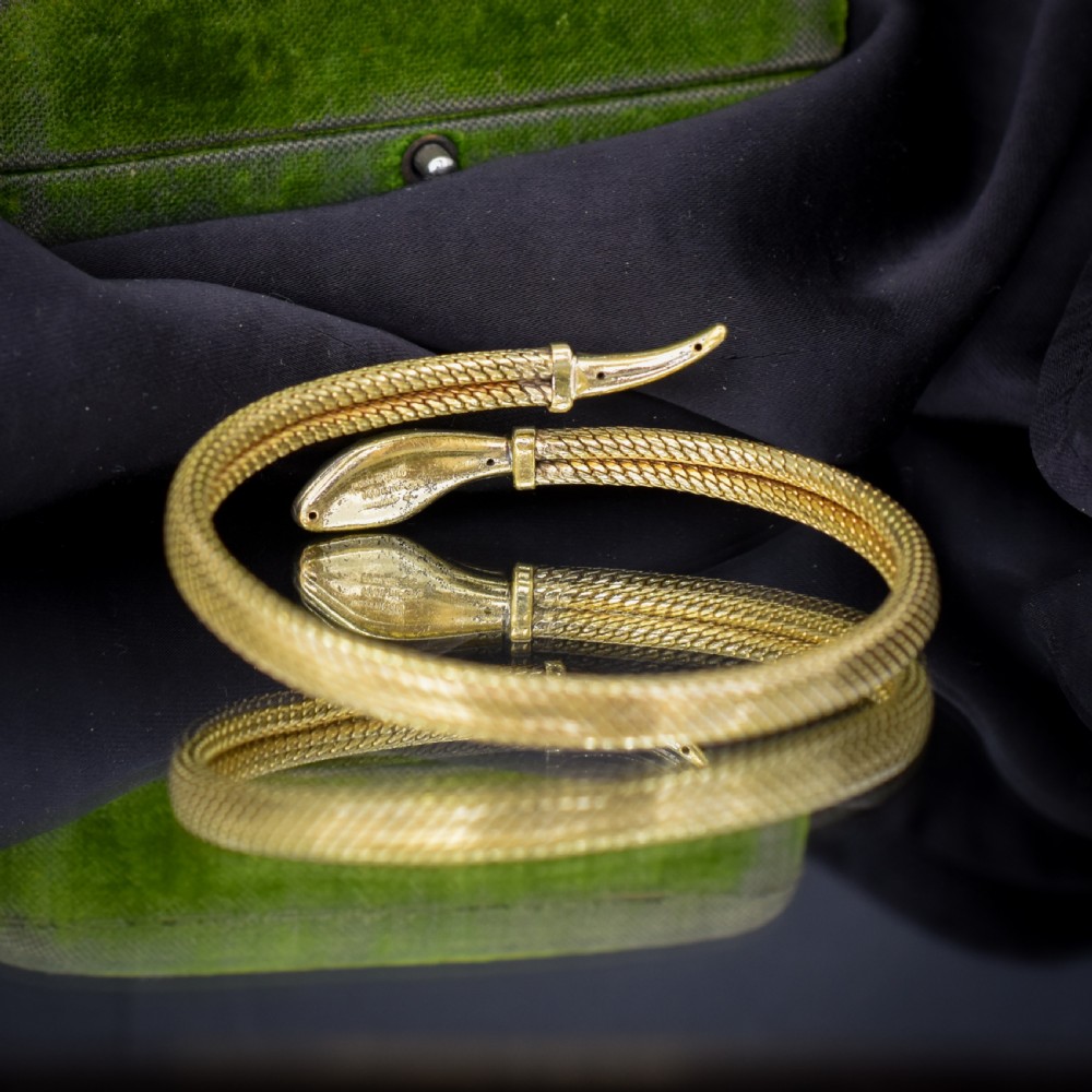 A rolled gold coiled snake bangle bracelet featuring detailed scale engraving, a sculpted head, and a tapered tail. View VI