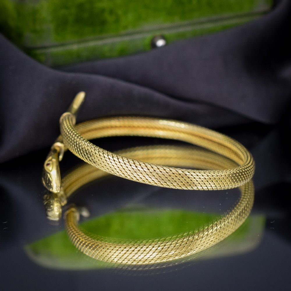 A rolled gold coiled snake bangle bracelet featuring detailed scale engraving, a sculpted head, and a tapered tail. View VII