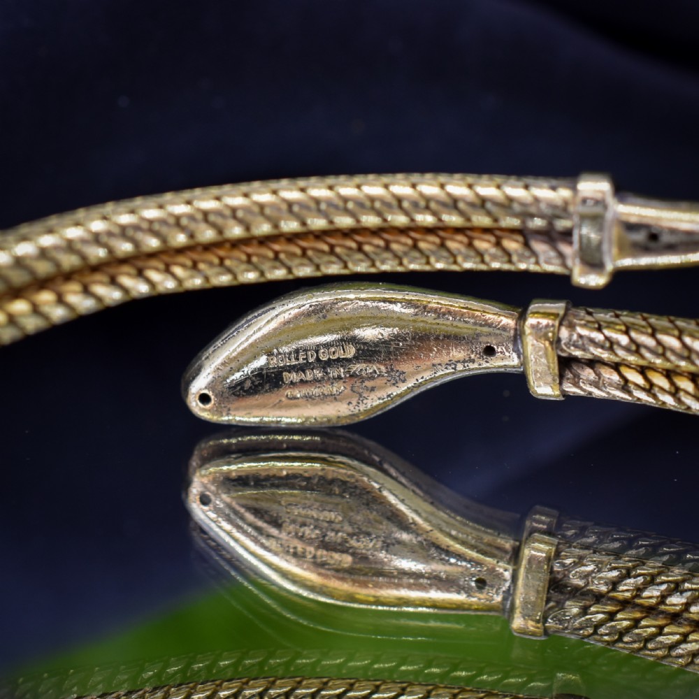 A rolled gold coiled snake bangle bracelet featuring detailed scale engraving, a sculpted head, and a tapered tail. View VIII