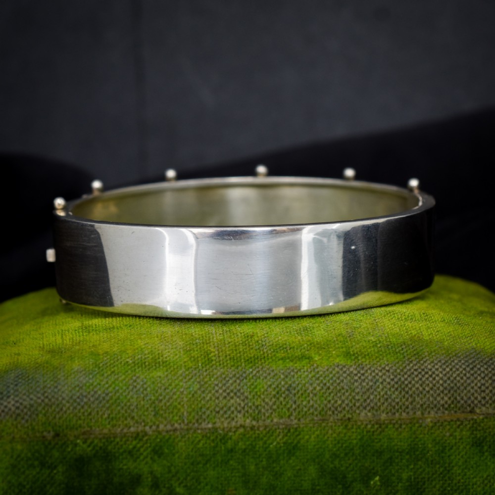A wide silver hinged cuff bangle featuring engraved floral foliage and applied gold bird motifs along the outer band. View III