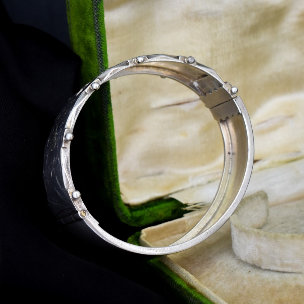 A wide silver hinged cuff bangle featuring engraved floral foliage and applied gold bird motifs along the outer band. View VII
