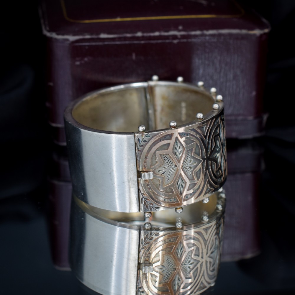 An antique Victorian wide hinged silver bangle decorated with hand-engraved geometric star motifs and a beaded upper and lower rim. View IV
