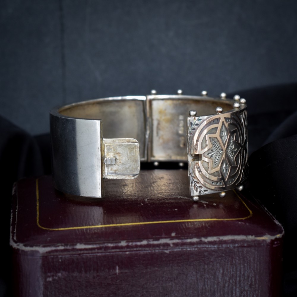An antique Victorian wide hinged silver bangle decorated with hand-engraved geometric star motifs and a beaded upper and lower rim. View VII