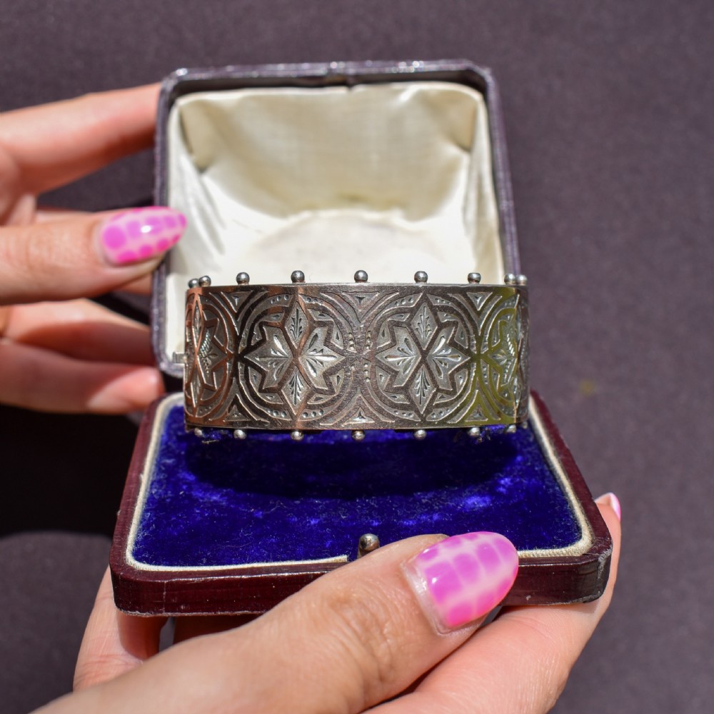 An antique Victorian wide hinged silver bangle decorated with hand-engraved geometric star motifs and a beaded upper and lower rim. View XII