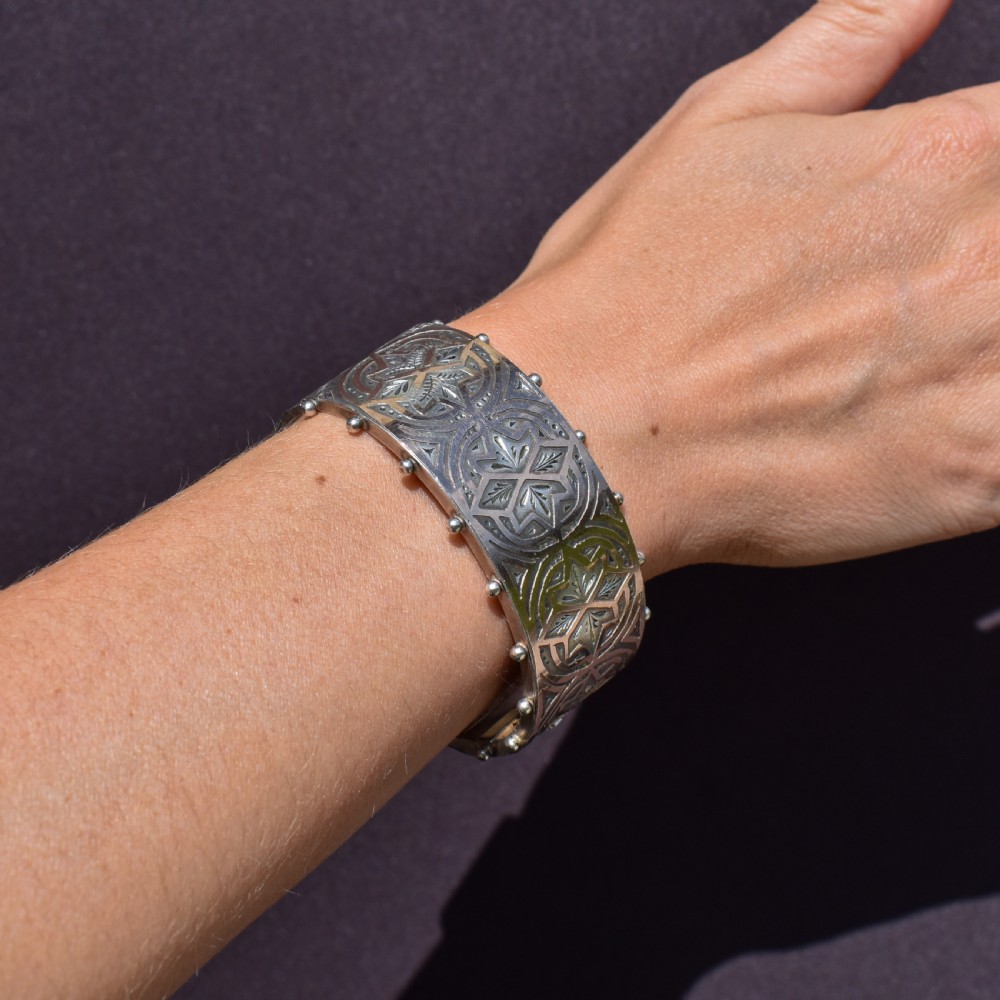 An antique Victorian wide hinged silver bangle decorated with hand-engraved geometric star motifs and a beaded upper and lower rim. View XIII