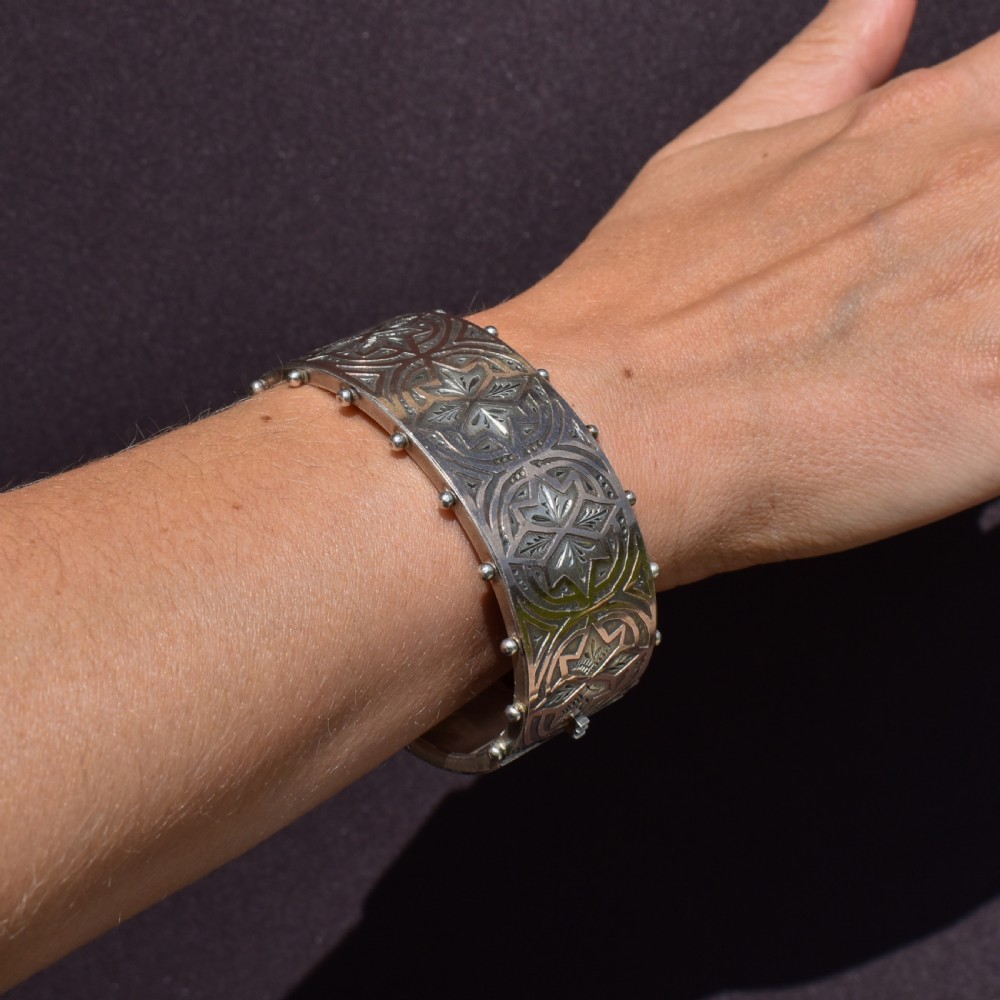 An antique Victorian wide hinged silver bangle decorated with hand-engraved geometric star motifs and a beaded upper and lower rim. View XIV