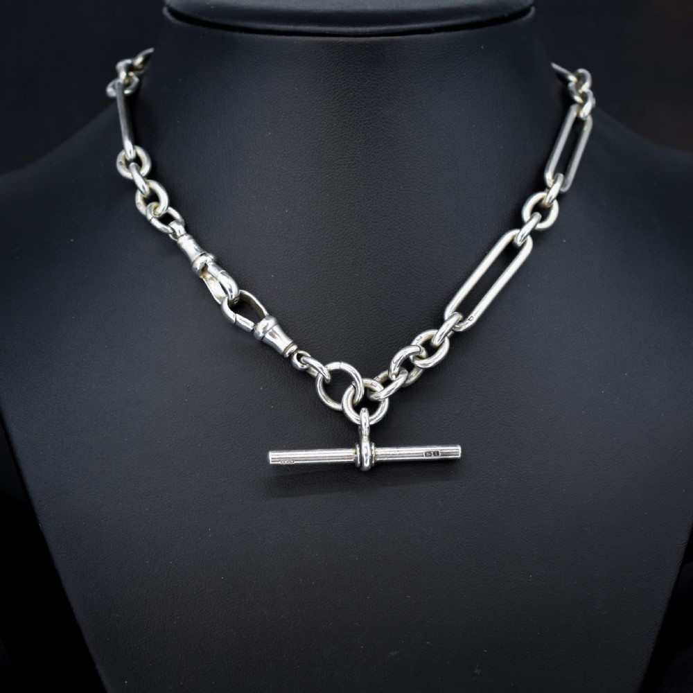 An antique Edwardian sterling silver trombone link Albert watch chain featuring a T-bar and swivel clasp displayed on a velvet background. View II