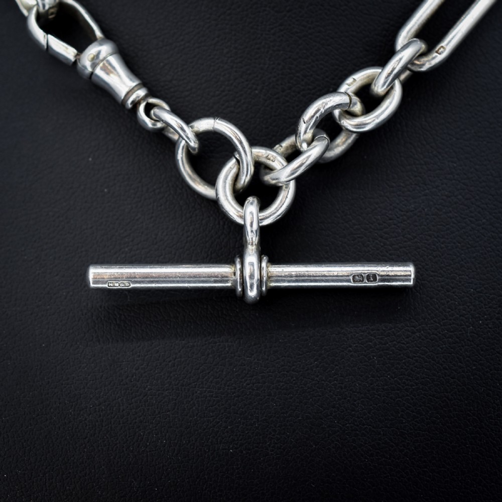 An antique Edwardian sterling silver trombone link Albert watch chain featuring a T-bar and swivel clasp displayed on a velvet background. View III