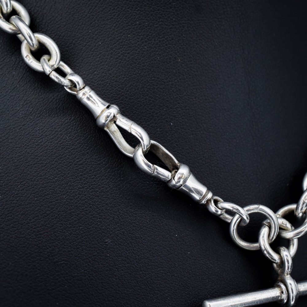 An antique Edwardian sterling silver trombone link Albert watch chain featuring a T-bar and swivel clasp displayed on a velvet background. View IV