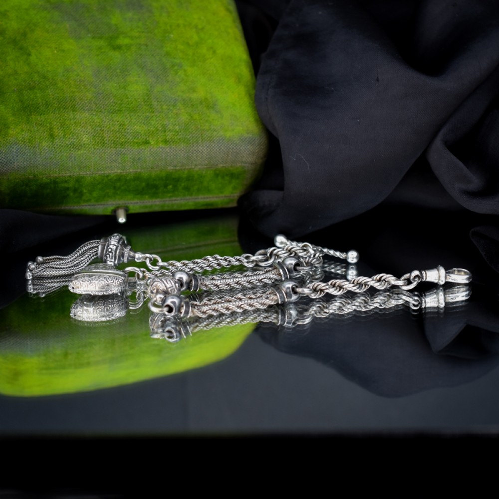 An antique silver Albertina watch chain styled as a bracelet, featuring multi-strand rope chains, an engraved heart motif charm, a silver tassel, a T-bar, and a swivel clasp. View II