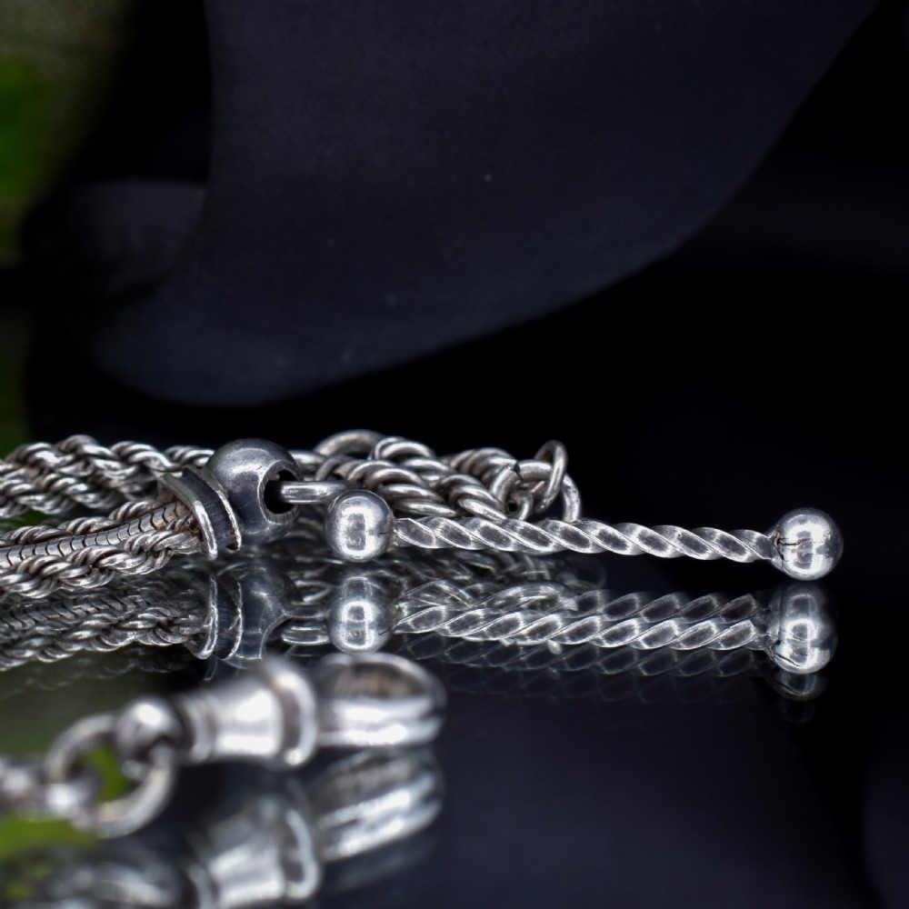 An antique silver Albertina watch chain styled as a bracelet, featuring multi-strand rope chains, an engraved heart motif charm, a silver tassel, a T-bar, and a swivel clasp. View III
