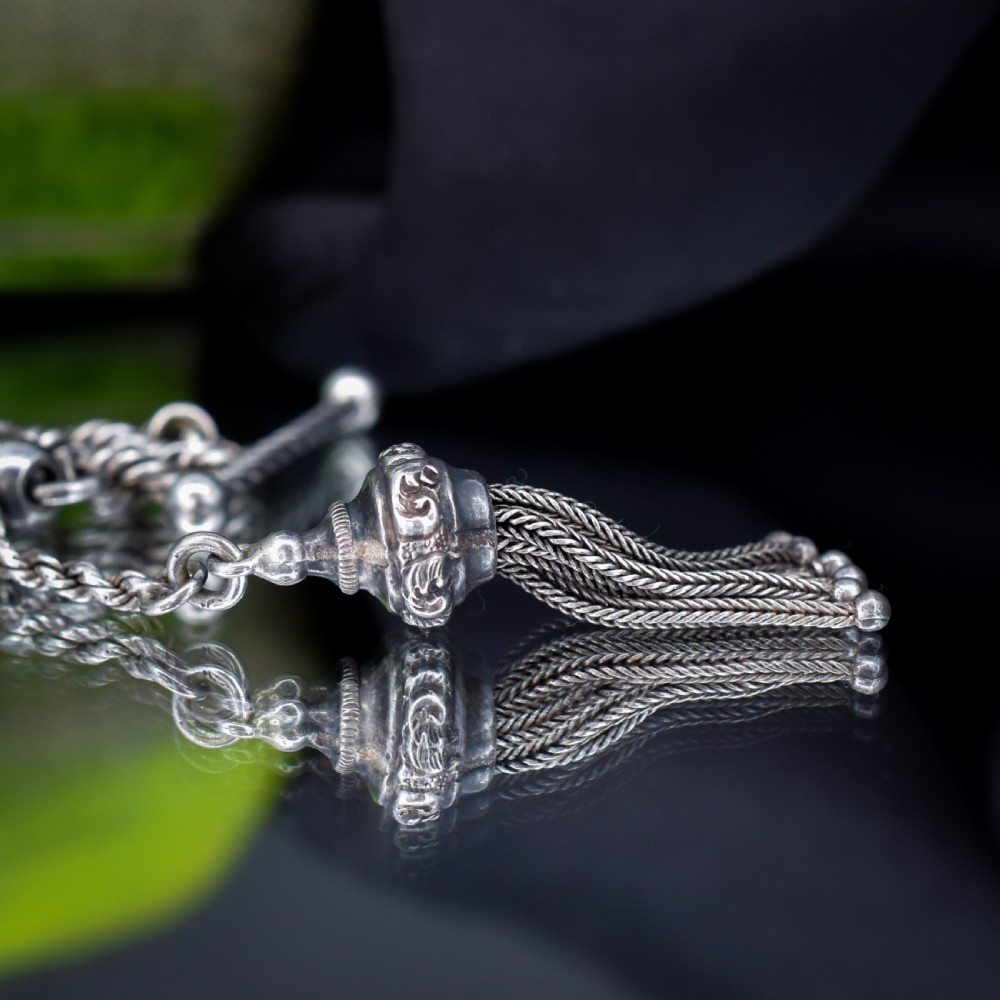An antique silver Albertina watch chain styled as a bracelet, featuring multi-strand rope chains, an engraved heart motif charm, a silver tassel, a T-bar, and a swivel clasp. View IV