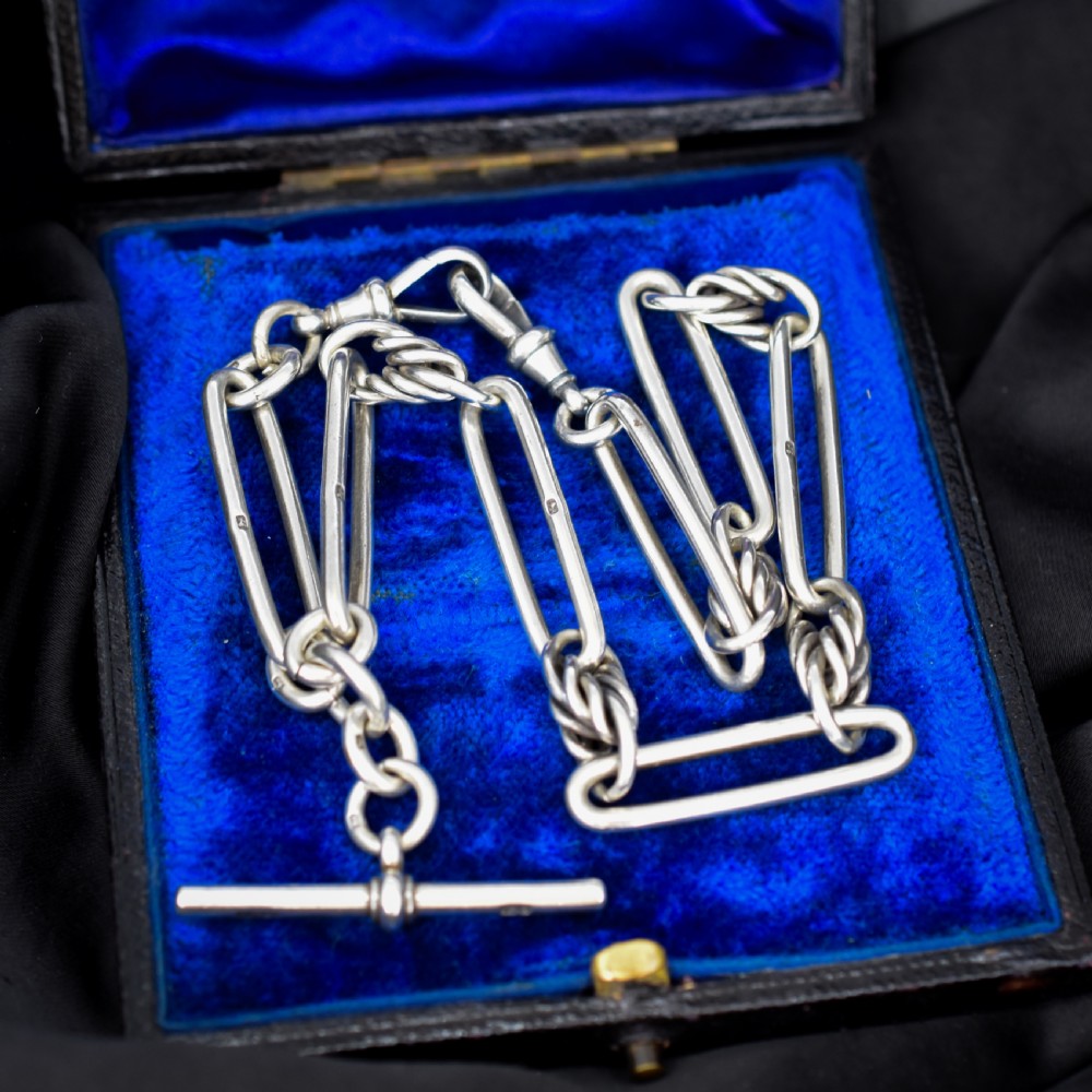 An antique Victorian sterling silver pocket watch chain featuring elongated trombone links, twisted love knot details, a T-bar, and a swivel clip. View II