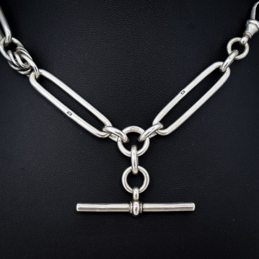 An antique Victorian sterling silver pocket watch chain featuring elongated trombone links, twisted love knot details, a T-bar, and a swivel clip. View V