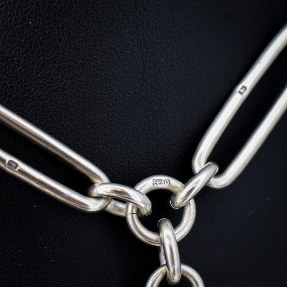 An antique Victorian sterling silver pocket watch chain featuring elongated trombone links, twisted love knot details, a T-bar, and a swivel clip. View VI