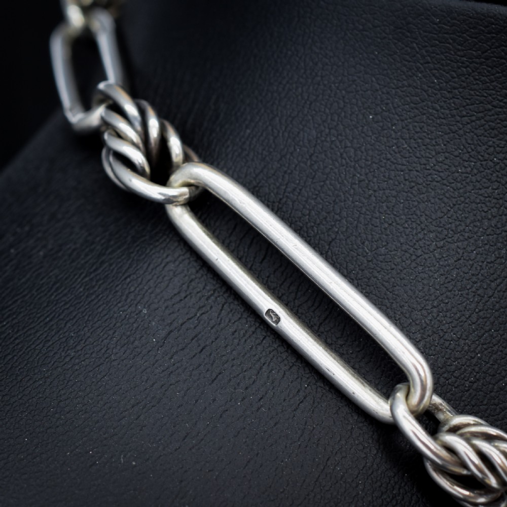 An antique Victorian sterling silver pocket watch chain featuring elongated trombone links, twisted love knot details, a T-bar, and a swivel clip. View VII