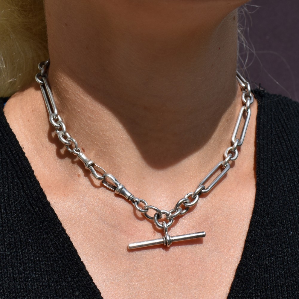 An antique Victorian sterling silver pocket watch chain featuring elongated trombone links, twisted love knot details, a T-bar, and a swivel clip. View IX