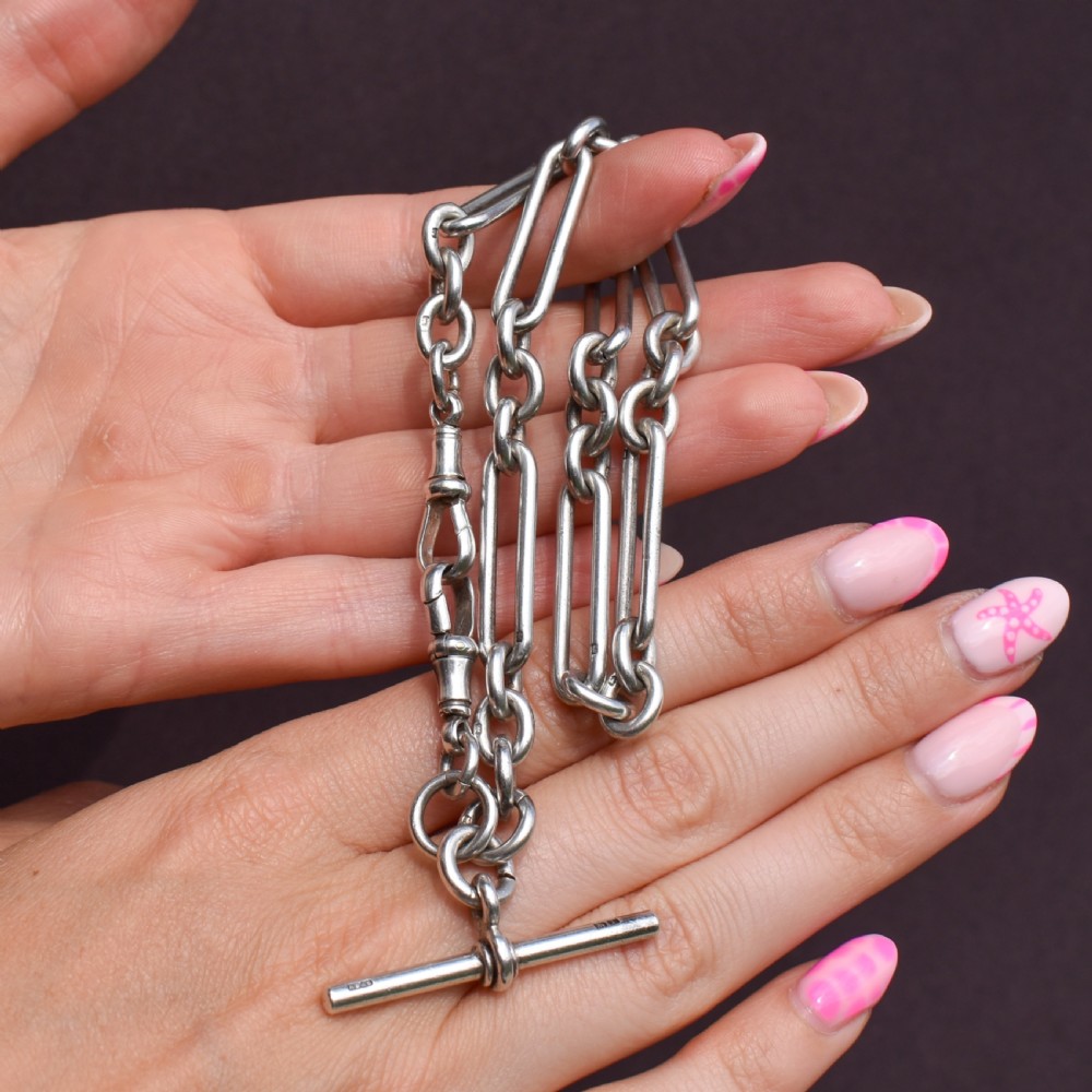 An antique Victorian sterling silver pocket watch chain featuring elongated trombone links, twisted love knot details, a T-bar, and a swivel clip. View X