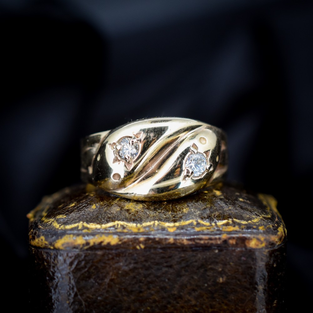 A yellow gold band featuring two entwined snake heads, each set with a star-engraved diamond.
