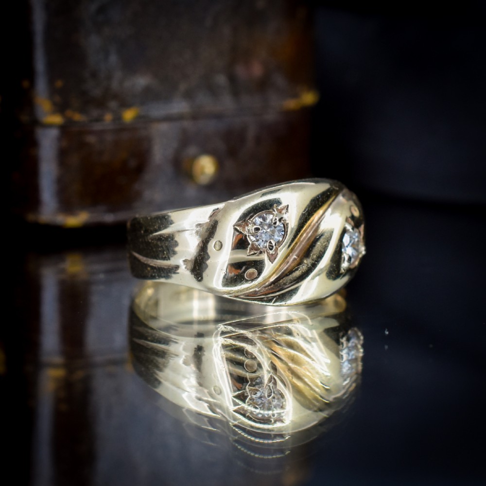 A yellow gold band featuring two entwined snake heads, each set with a star-engraved diamond. View IV