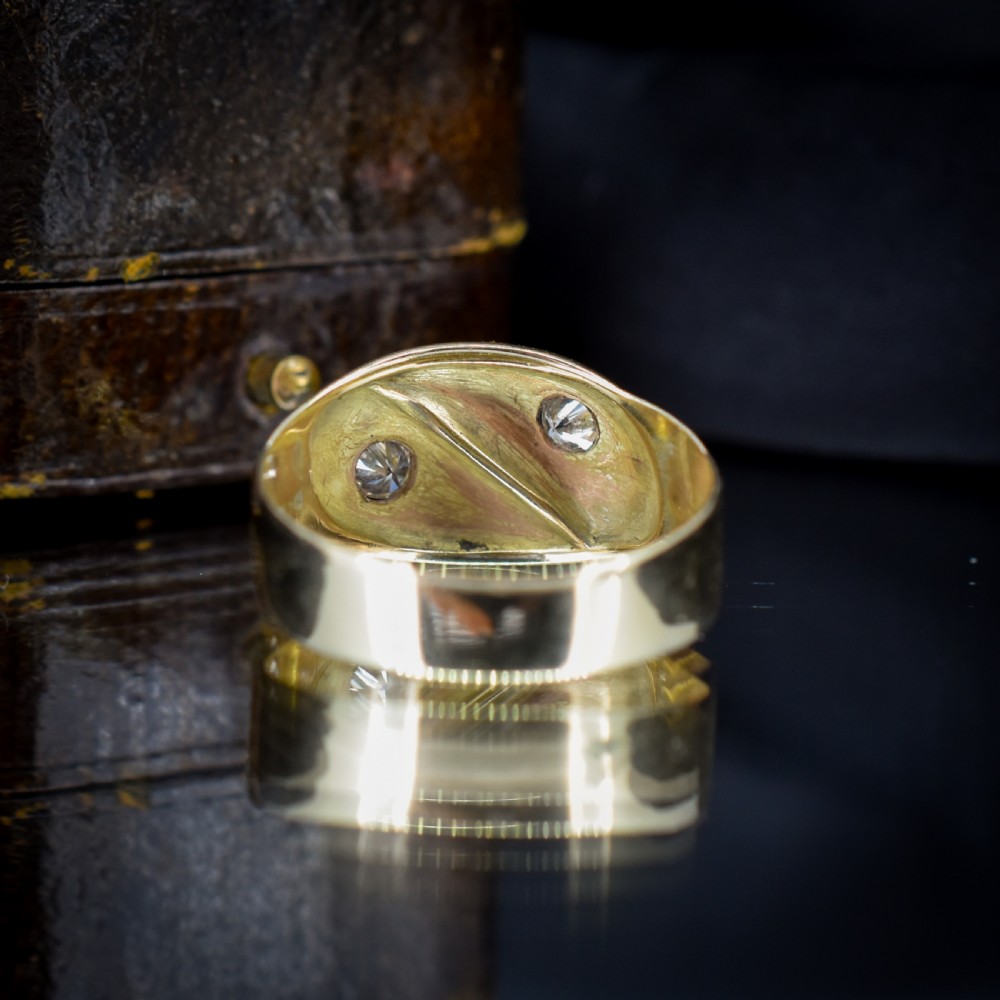 A yellow gold band featuring two entwined snake heads, each set with a star-engraved diamond. View V
