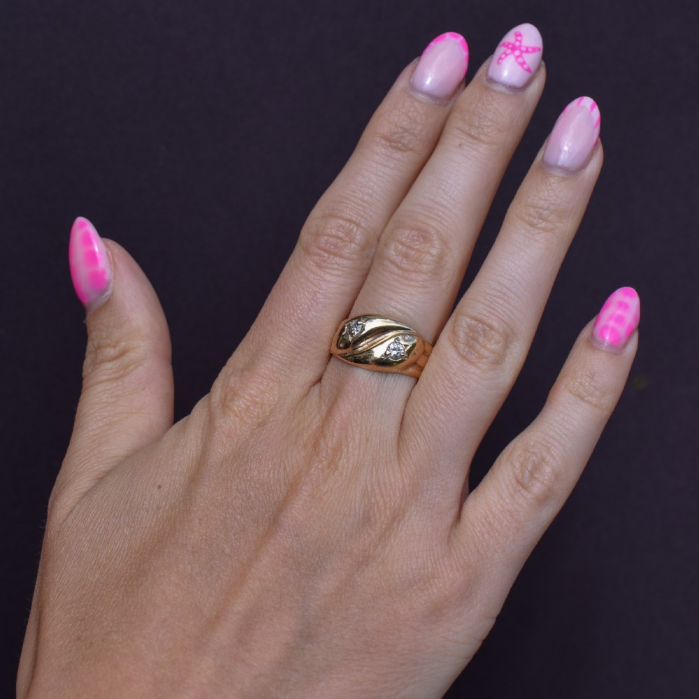 A yellow gold band featuring two entwined snake heads, each set with a star-engraved diamond. View IX