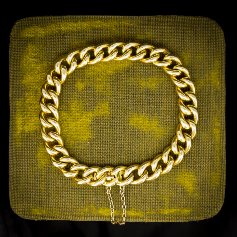 An 18ct yellow gold curb link bracelet featuring a concealed box clasp and an attached safety chain.